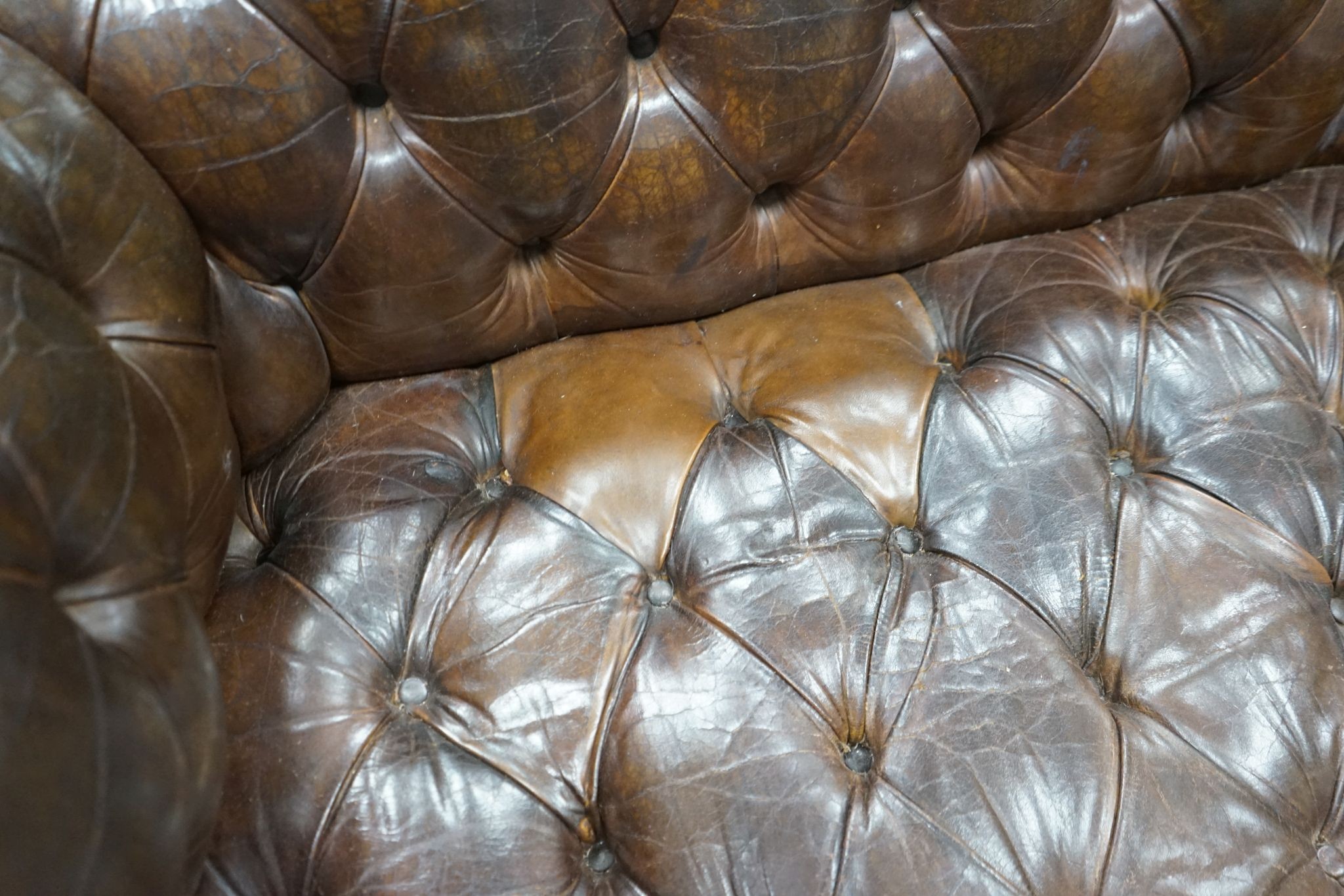 An early 20th century Chesterfield settee upholstered in deep buttoned brown leather, length 200cm, depth 90cm, height 72cm